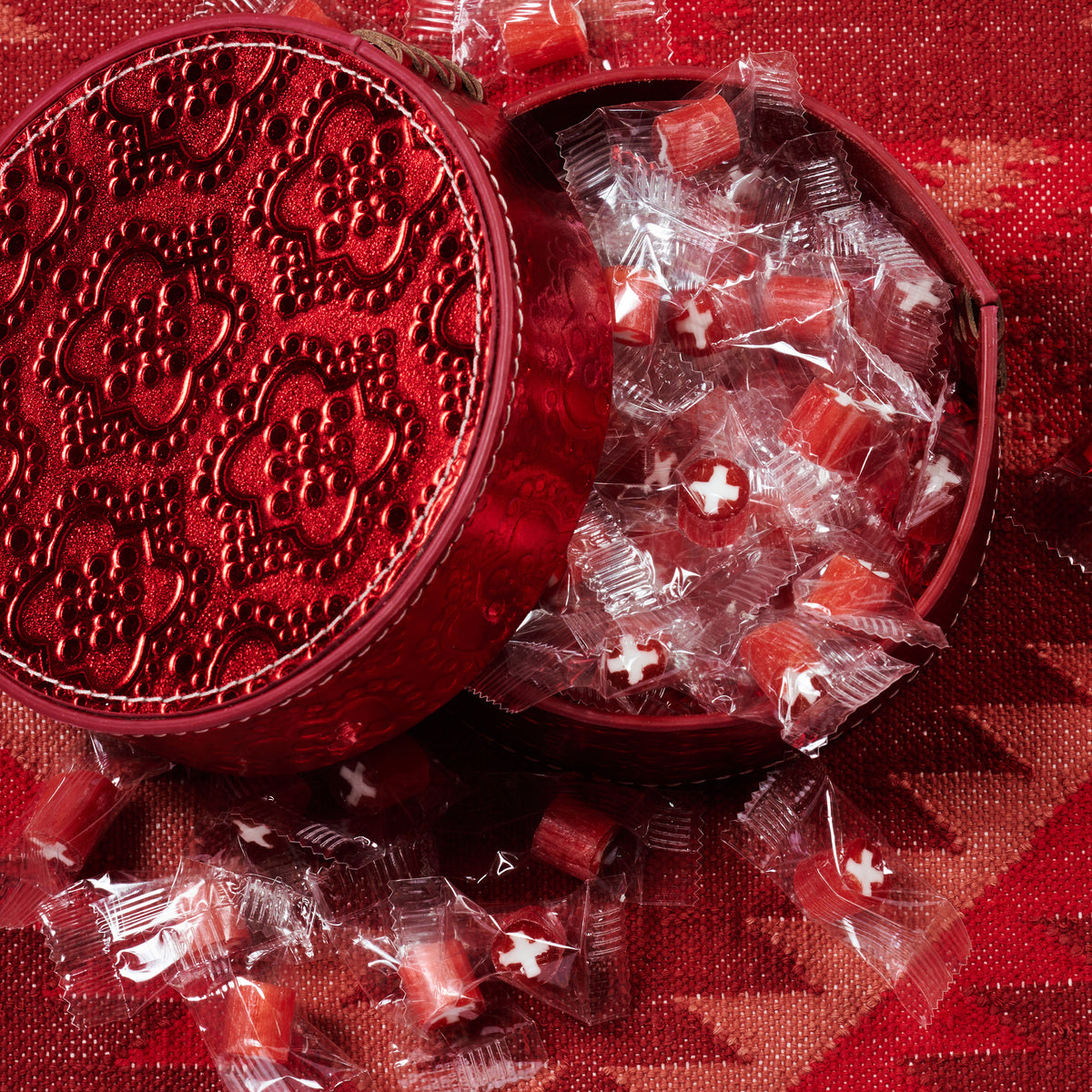 Dose rund flach ICON aus Leder geprägt in rot, gefüllt mit swiss bonbons
