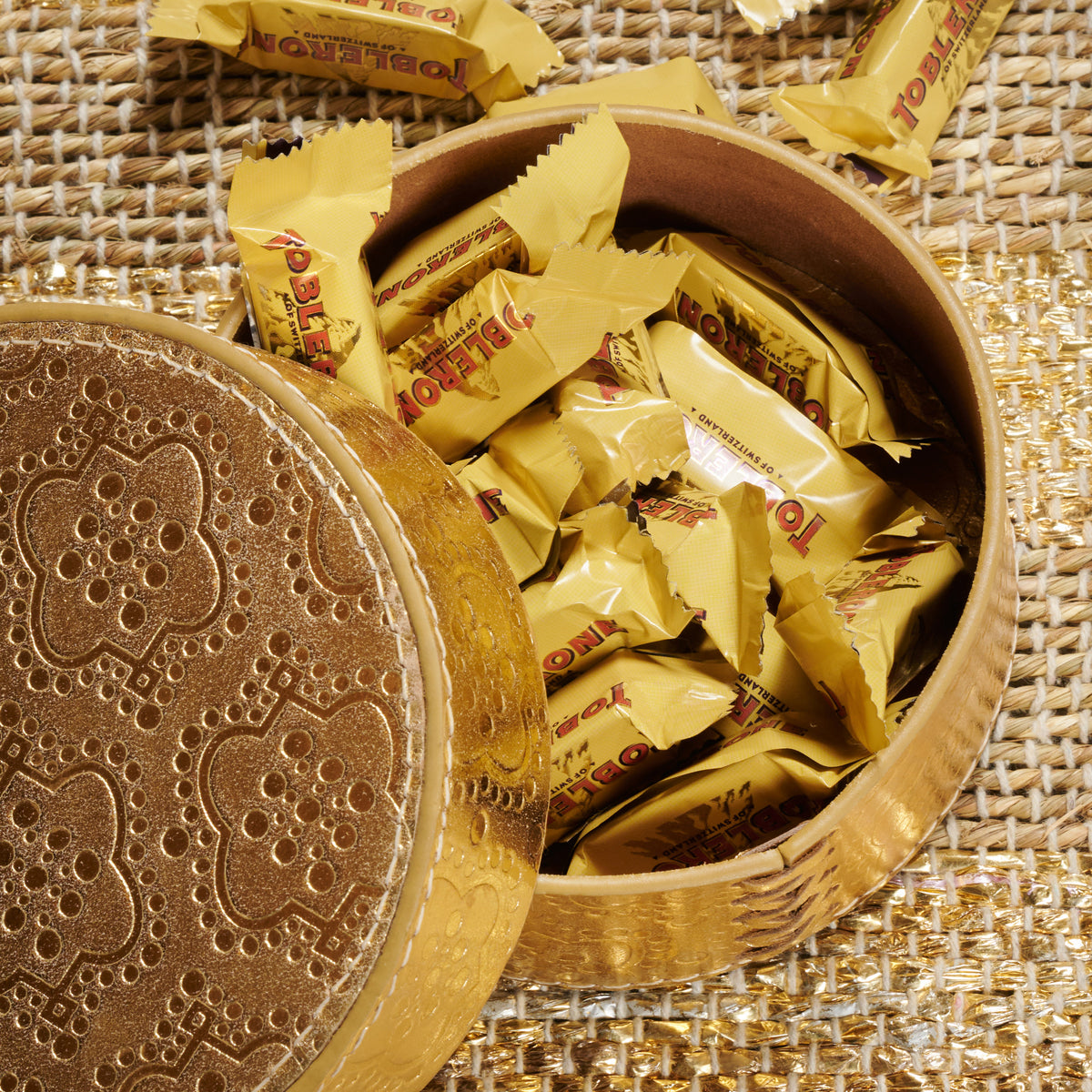 Dose rund flach ICON aus Leder geprägt in gold, gefüllt mit toblerone schokolade