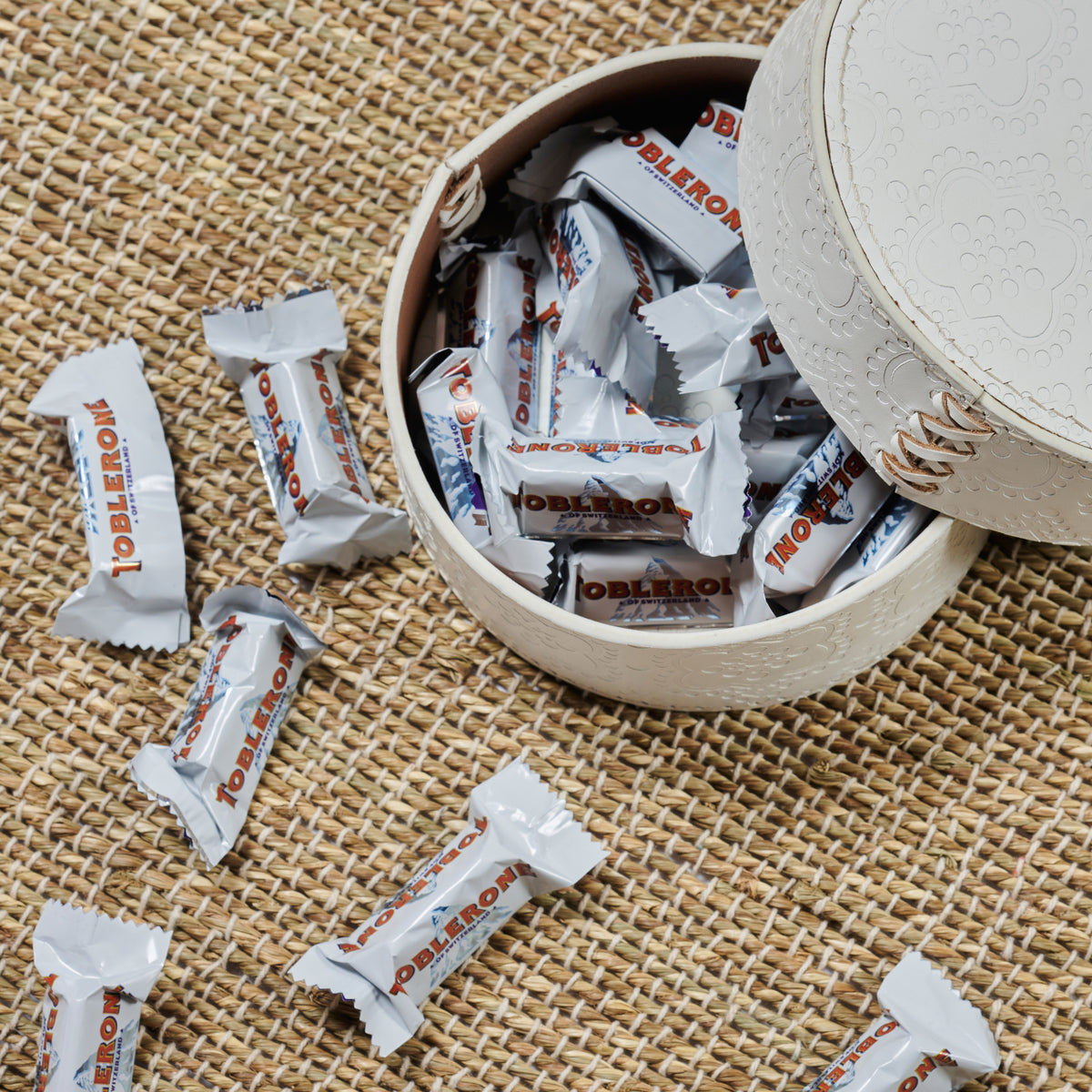 Dose rund flach ICON aus Leder geprägt in weiss, gefüllt mit Toblerone Schokolade