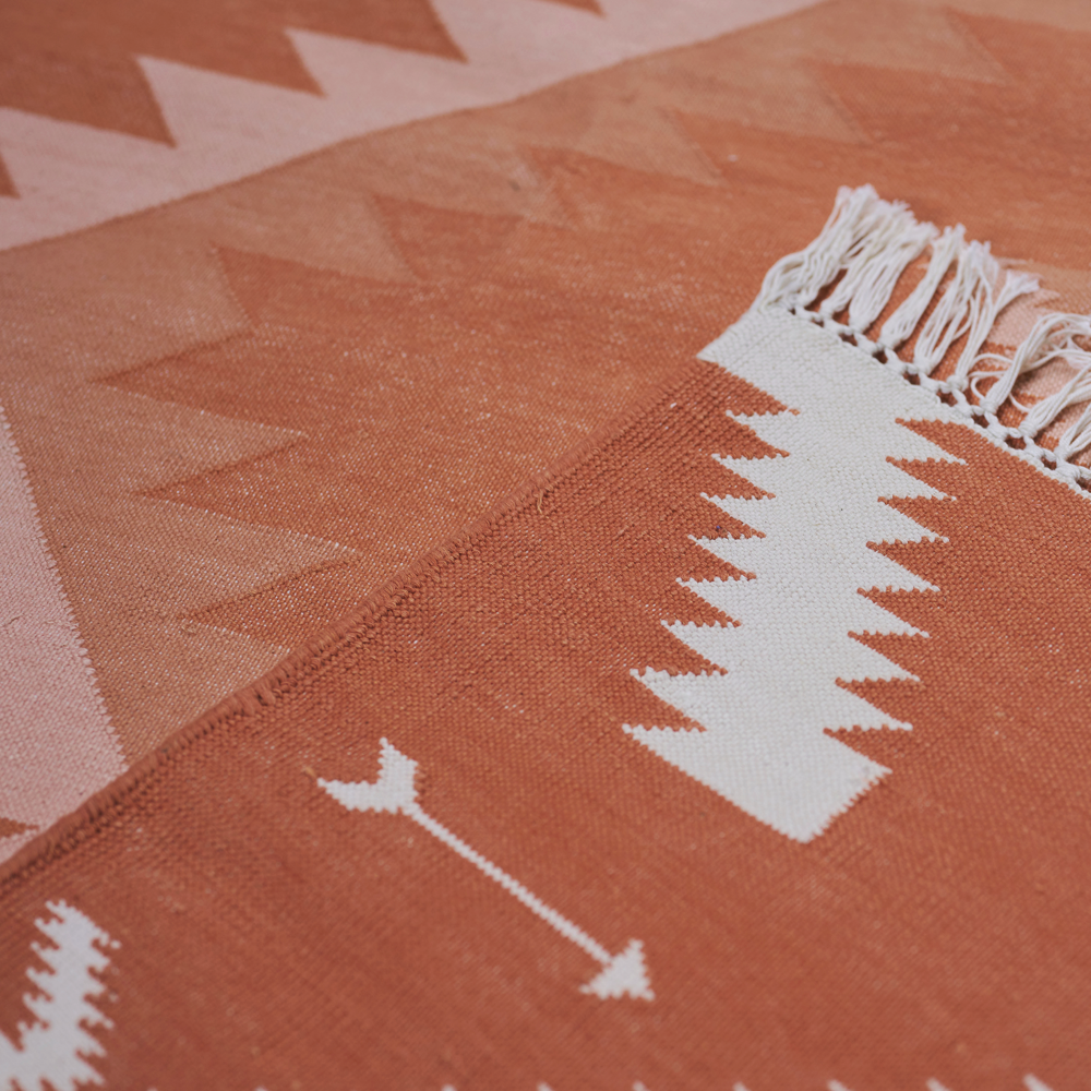 Der handgewobene &#39;Dhurrie&#39; Teppich, inspiriert von der Navajo-Kultur, wird in Rajasthan gefertigt. Er ist aus 100% Baumwolle und hat auf zwei Seiten einen Fransen-Abschluss. Der Teppich ist in 2 verschiedenen Grössen und in diversen Farbkombinationen erhältlich. Die Teppiche können leichte Farbabweichungen sowie Masstoleranzen +/- 5cm aufweisen. Die Masse sind ohne Fransen berechnet.