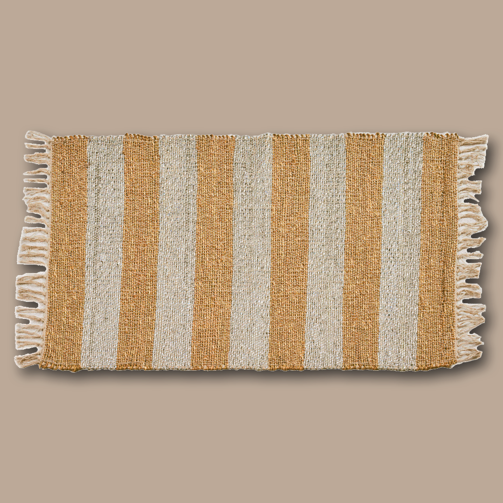 Der handgewobene Teppich wird in Rajasthan aus Seegras gefertigt und hat auf zwei Seiten einen Fransen-Abschluss. Der Teppich ist in zwei verschiedenen Farben, gold und silber, erhältlich. Durch sein natürliches Material kann das Produkt leichte Farbabweichungen sowie Masstoleranzen aufweisen.